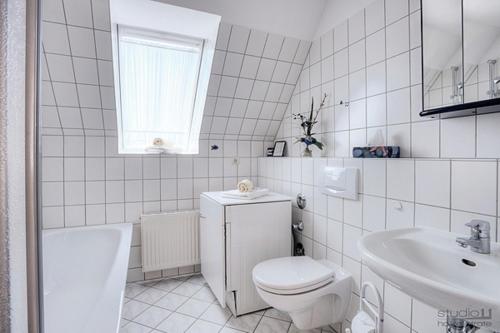 a white bathroom with a toilet and a sink at Ostseewelle Whg 7 in Zingst
