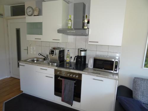 a kitchen with white cabinets and a sink and a microwave at 5-Sterne-Fewo "Facette" in Allenbach