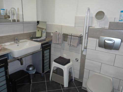 a bathroom with a sink and a toilet and a stool at 5-Sterne-Fewo "Facette" in Allenbach
