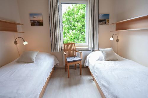 a bedroom with two beds and a chair and a window at Zur schönen Aussicht - FW 6 in Dahme