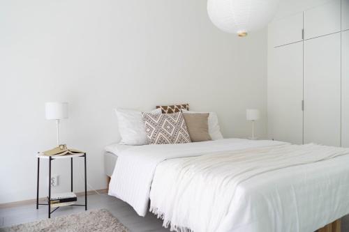 a white bedroom with a large white bed with white walls at NEW stylish 2br apartment in the city center in Oulu