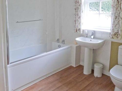 a white bathroom with a tub and a sink at 2 Dalegarth in Skipton