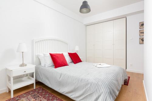 Dormitorio blanco con cama blanca y almohadas rojas en Apartments Westfield Arkadia Burakowska by Renters, en Varsovia