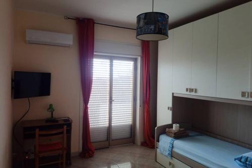 Schlafzimmer mit einem Bett und einem Fenster mit roten Vorhängen in der Unterkunft Casa Helios in Lentini