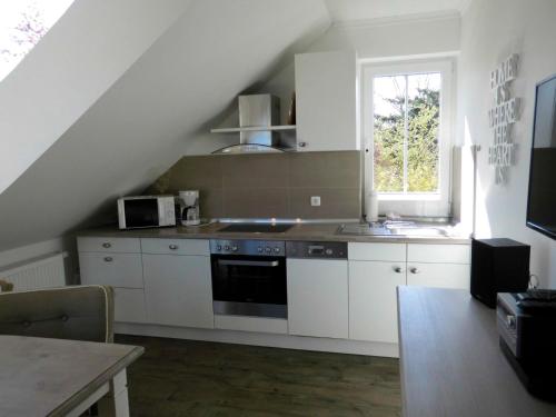 een keuken met witte kasten, een wastafel en een raam bij LANDHAUS AM SUND im OG in Heiligenhafen