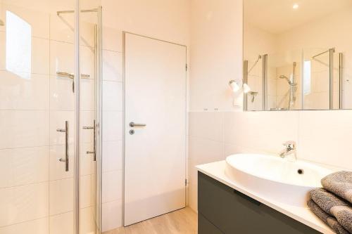 een witte badkamer met een wastafel en een douche bij W3 - Gästehaus Christian-Westphal-Str 60 - FERIENDOMIZIL HOLLICH in Grömitz