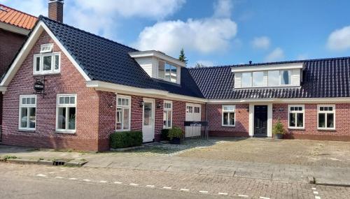 a red brick house with a black roof at De Oude Smederij voor 2 personen in 't Veld in De Leijen