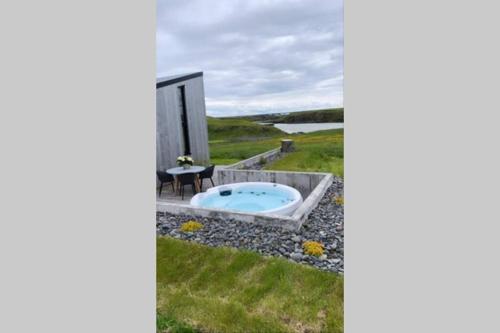a jacuzzi tub in a yard next to a house at Urriðafoss Waterfall Lodges in Selfoss