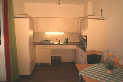 a small kitchen with white cabinets and a table at Setzberg in Bad Wiessee