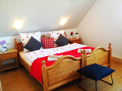 a bedroom with a wooden bed with red sheets and blue pillows at Hotel Landgasthof Sonne in Mahlberg