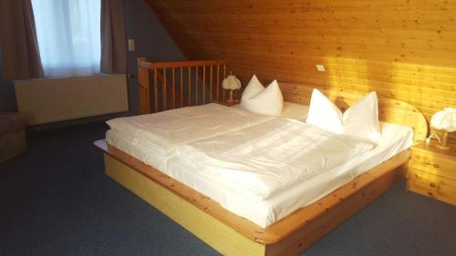 オストゼーバート・ゼリンにあるFerienhaus Kreß linksの木製ベッド(白いシーツ、枕付)