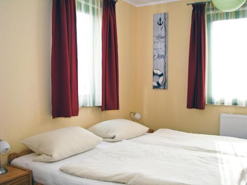 a bedroom with two white beds with red curtains at Hütigendachs, FW 4 in Zingst