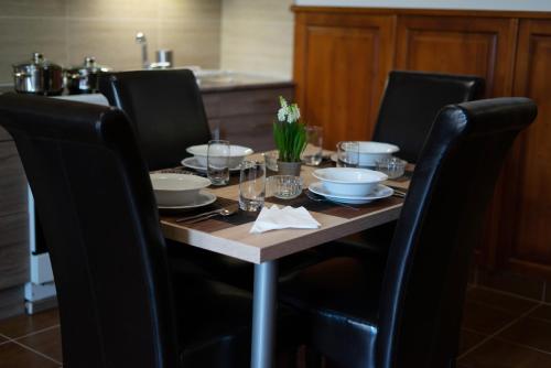 stół z krzesłami i stół z naczyniami w obiekcie Prána Apartman w mieście Herend