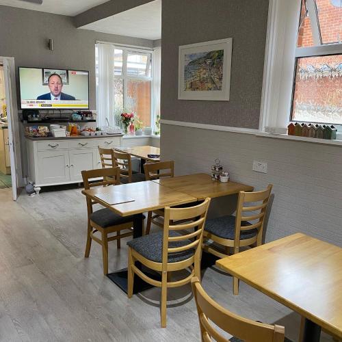 a restaurant with wooden tables and chairs and a tv at Inglewood Guest House in Sandown