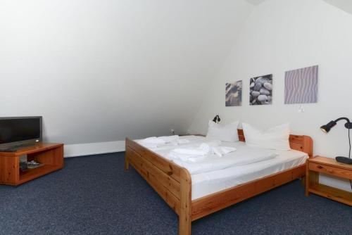 ヴィーク・アウフ・フェールにあるHaus Fünen Whg 03のベッドルーム(白いシーツ付きのベッド、テレビ付)