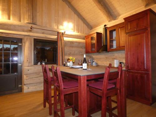 a kitchen with a table with chairs and a bottle of wine at Naturstammhaus Tollensesee in Krickow