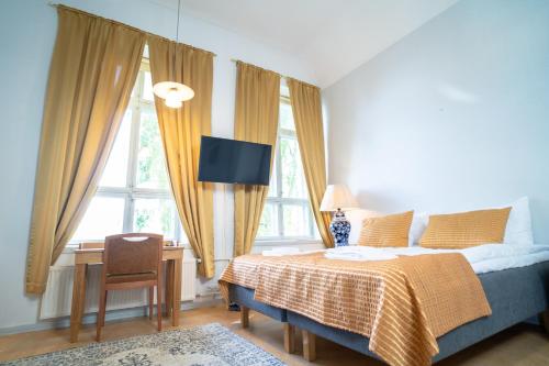Schlafzimmer mit einem Bett, einem Schreibtisch und Fenstern in der Unterkunft Boutique Hotel Willa Aria in Savonlinna