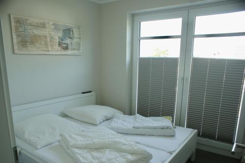 two beds in a white room with a window at Fehmarn-OstseeferienStrandresidenz Vogelflug 14312 in Fehmarnsund