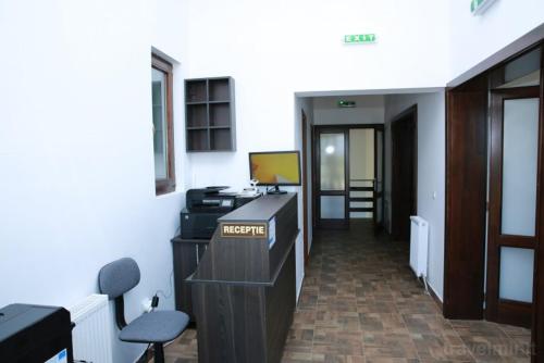 una oficina con escritorio, ordenador y sillas en Pensiunea Rosia, en Roşia