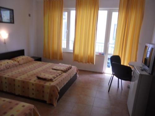 a hotel room with two beds and a television at Клуб "Агато-полис"-стаи за семейна почивка in Ahtopol