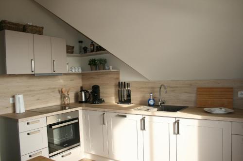 a kitchen with white cabinets and a sink at Whg 17 - De Mügg in Zingst