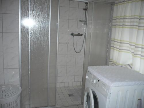 een badkamer met een douche en een wasmachine bij Ferienwohnung Familie Renken in Marienhafe