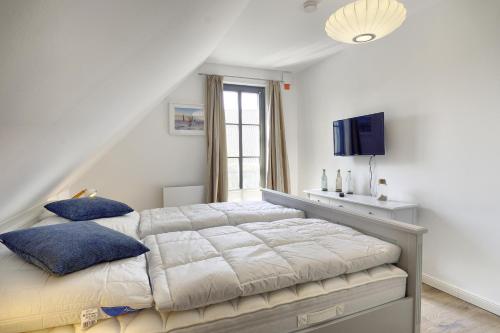 a bedroom with a large bed and a tv at Sanya in Zingst