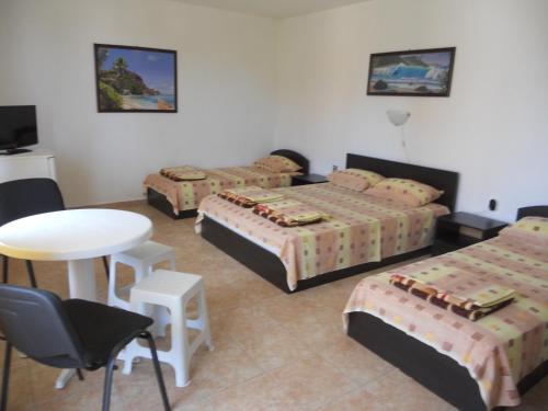 um quarto de hotel com três camas e uma mesa e cadeiras em Стаи под наем "Таня"- безплатен паркинг на 100 метра em Ahtopol