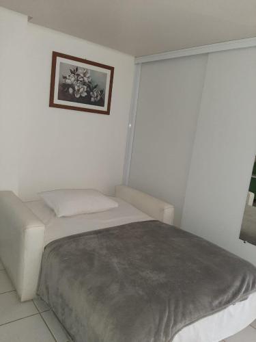 a white bedroom with a bed and a picture on the wall at Pipa´s Ocean Flat in Pipa