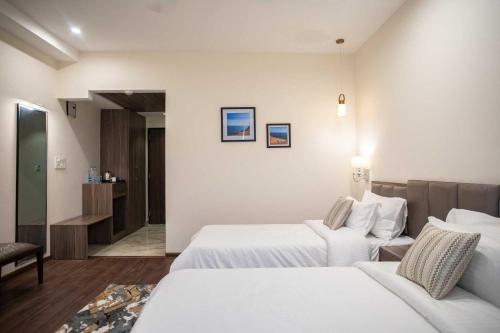 a hotel room with two beds and a couch at Hotel Alaya in Dehradun