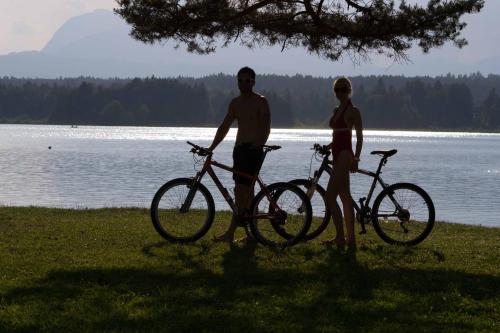 two men standing next to their bikes in front of a lake at Pension Stissen Haus am See in Faak am See