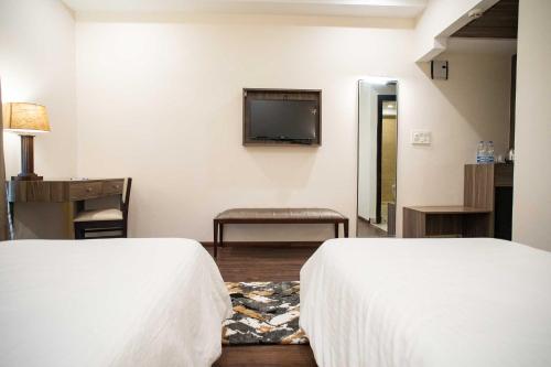 a hotel room with two beds and a television at Hotel Alaya in Dehradun