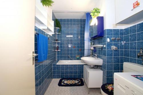 a blue tiled bathroom with a tub and a sink at Private Rooms in Hannover