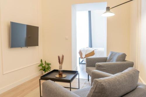 ein Wohnzimmer mit 2 Stühlen und einem TV an der Wand in der Unterkunft Suites Alfonso X in Jerez de la Frontera