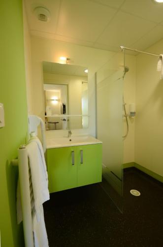 a green bathroom with a sink and a shower at Hôtel la Verriaire - The Originals in La Verrie