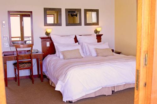 1 Schlafzimmer mit einem Bett mit einem Schreibtisch und einem Bett mit einem sidx sidx sidx in der Unterkunft Sandford Park Country Hotel in Bergville