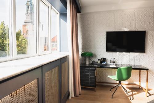 a room with a desk and a television and a green chair at Hotel Skt Petri in Copenhagen