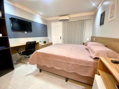 um quarto com uma cama, uma secretária e uma televisão em Apartamento Studio Centro de Macapá em Macapá