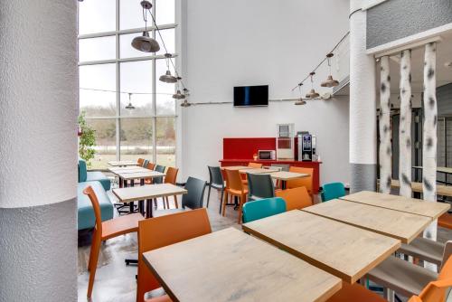 a restaurant with wooden tables and chairs andwindows at HotelF1 Bourges Le Subdray in Bourges