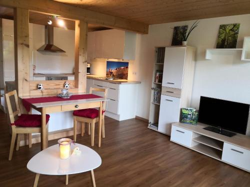 ein Wohnzimmer mit einem Tisch und einer Küche in der Unterkunft Ferienwohnung Belchenliebe in Schönenberg