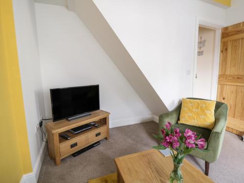 a living room with a tv and a chair and a table at Herdwick Heaf in Cleator