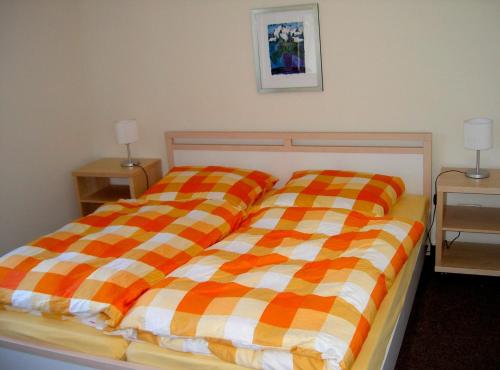 a bed with an orange and yellow plaid blanket at Ferienhaus Bergstädt "Utspann" in Westerbergen