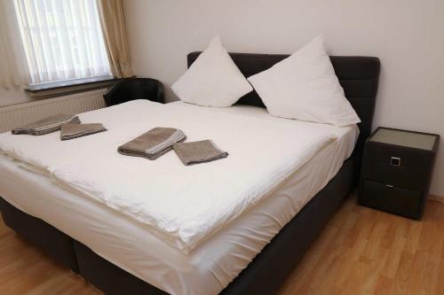 Una cama con sábanas blancas y dos libros. en Aparthotel Kompass A 304, en Essen