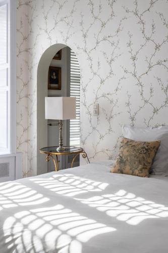 a bedroom with a bed and a table with a lamp at Molenmeers Boutique Guesthouses in Bruges