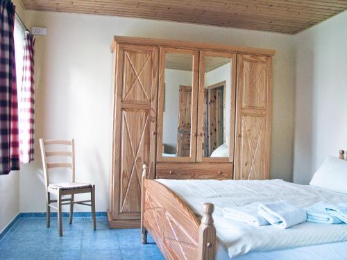 a bedroom with a bed and a wooden cabinet and a chair at Ihrgistern, FW 2 in Zingst
