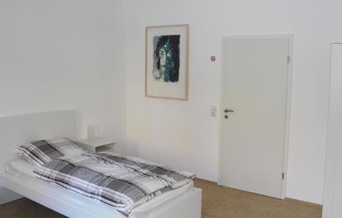 a white bedroom with a bed and a picture on the wall at Haus Roy - Ferienwohnung Erdgeschoß in Zülpich