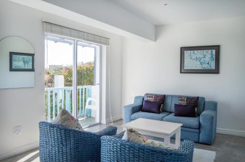 a living room with a blue couch and a table at Bellamente Sirene in Gansbaai