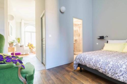 a bedroom with a bed and a green chair at La Chassagne, en plein cœur de ville in Dijon