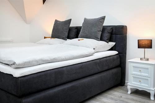 eine schwarze Couch mit Kissen darüber in der Unterkunft Seen-Apartment im Herrenhaus Rheinblick in Xanten