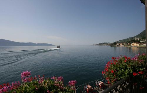 un barco en un gran cuerpo de agua con flores en Hotel Garnì Riviera, en Gargnano